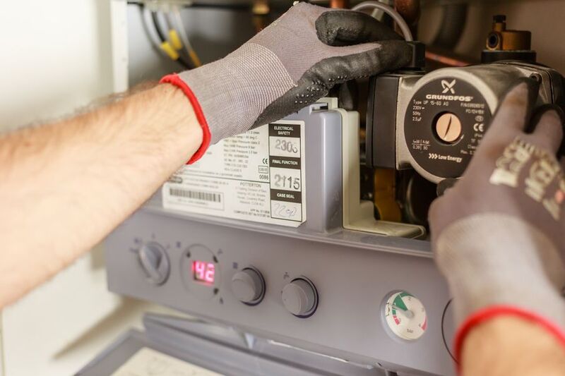Hands servicing a water heater unit